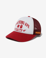 RED::A red mesh cap with a white front panel with the words 'A Bathing Ape' above he Undefeated and Bape logos above the letters 'UACTP' on a white background.